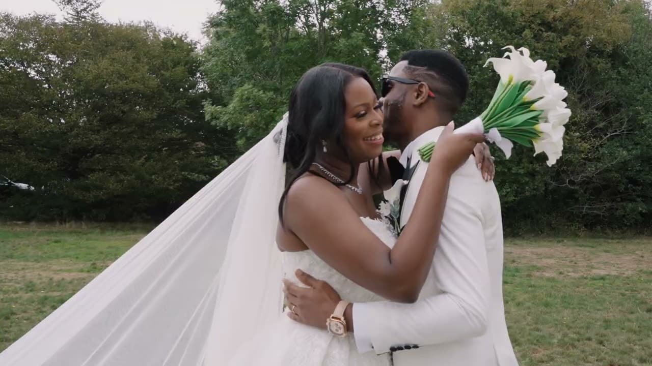 The couple embracing in an open field, her veil streaming out to one side, a bouquet of white calla lilies raised behind his shoulder.