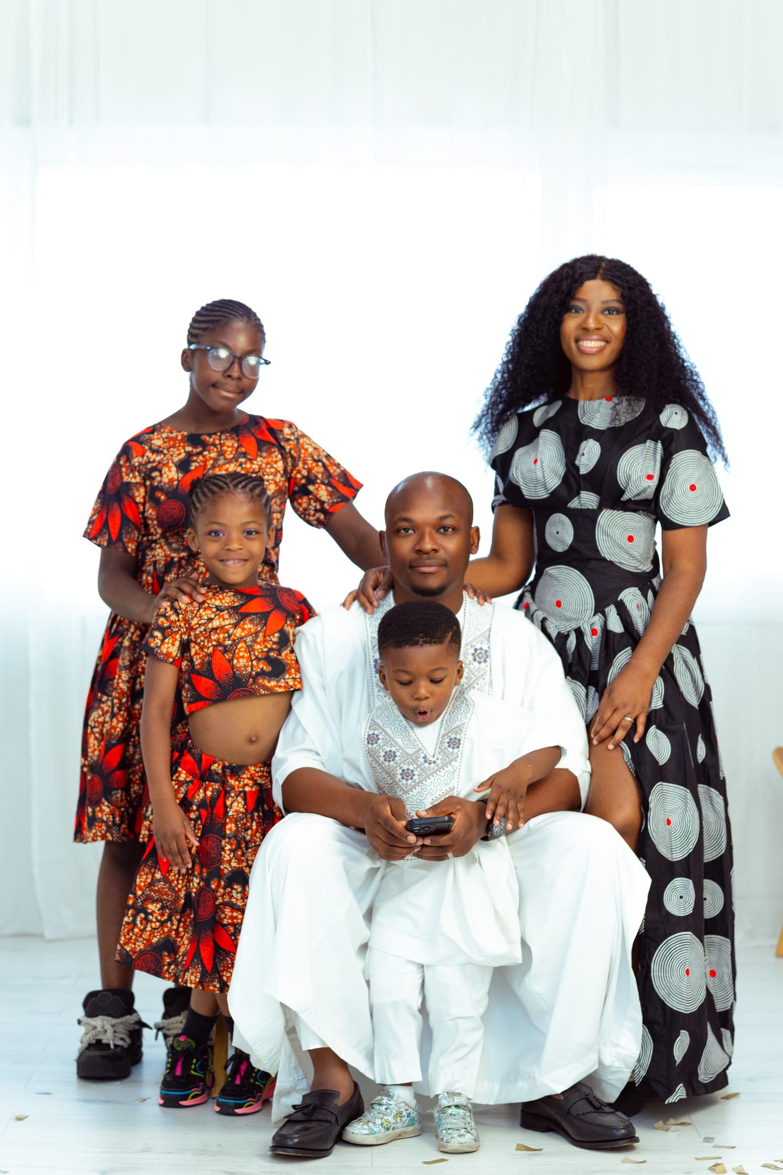 The family in coordinated print — the two daughters in orange and red, his wife in black and white, the children's father seated at the centre with their son.