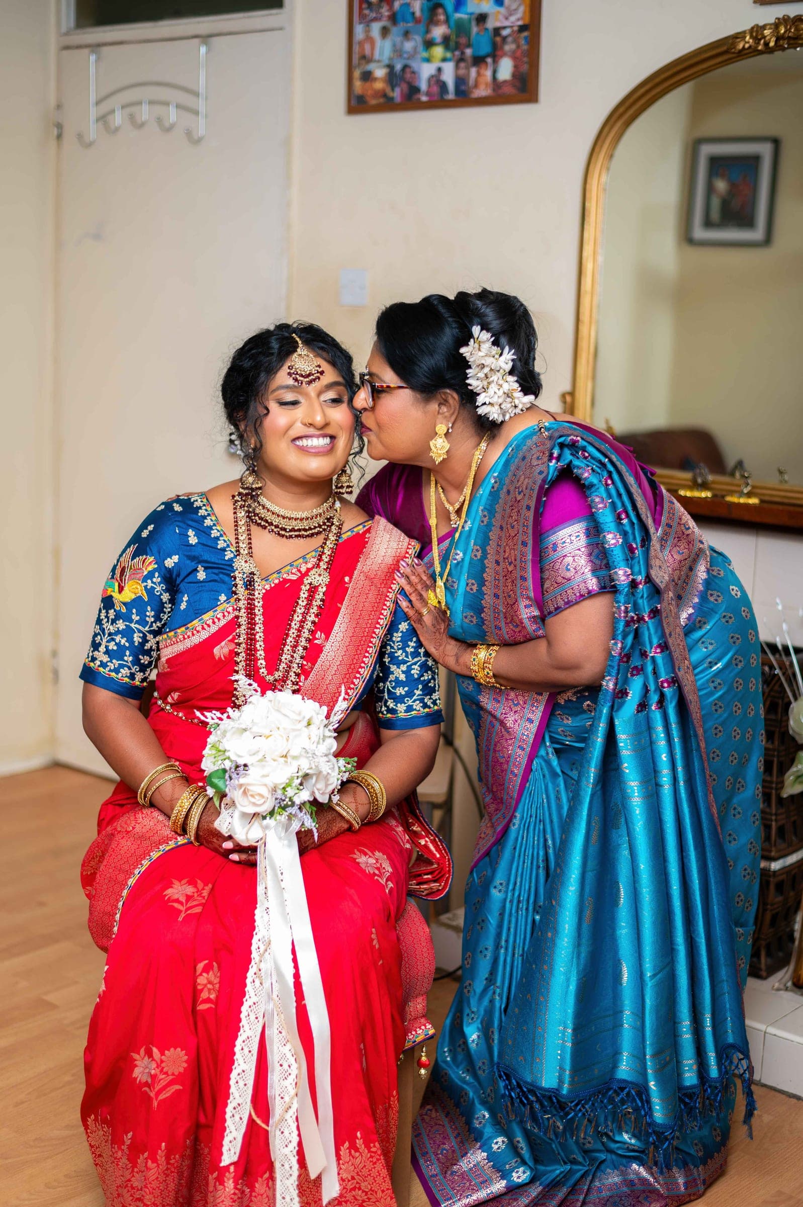 Her mother leans down to kiss her temple; the bride closes her eyes and laughs.