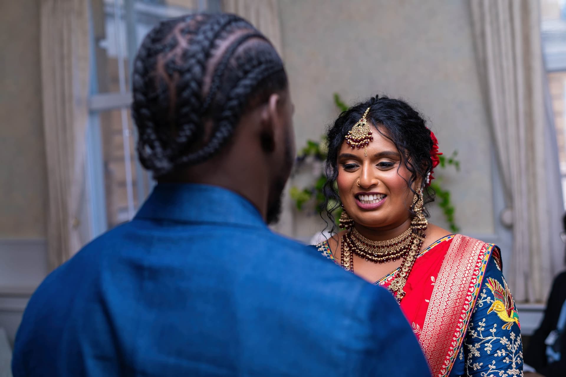 Framed over the groom's shoulder, the bride looks at him and breaks into a smile.