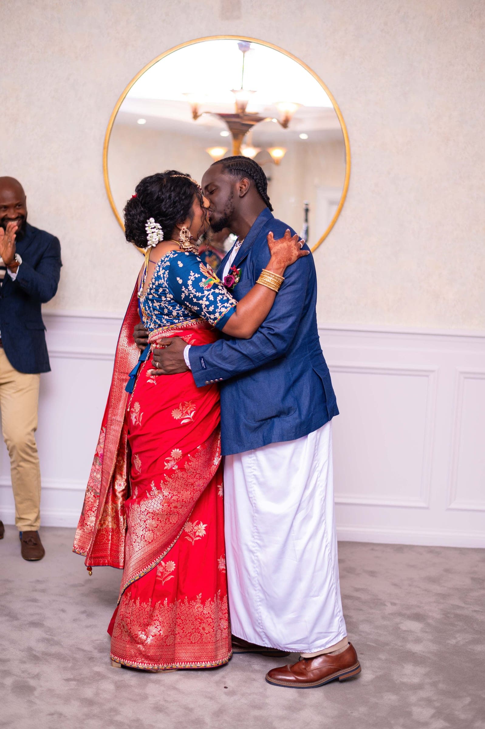 The first kiss, her hennaed hand on his shoulder, the officiant applauding at the edge of the frame.