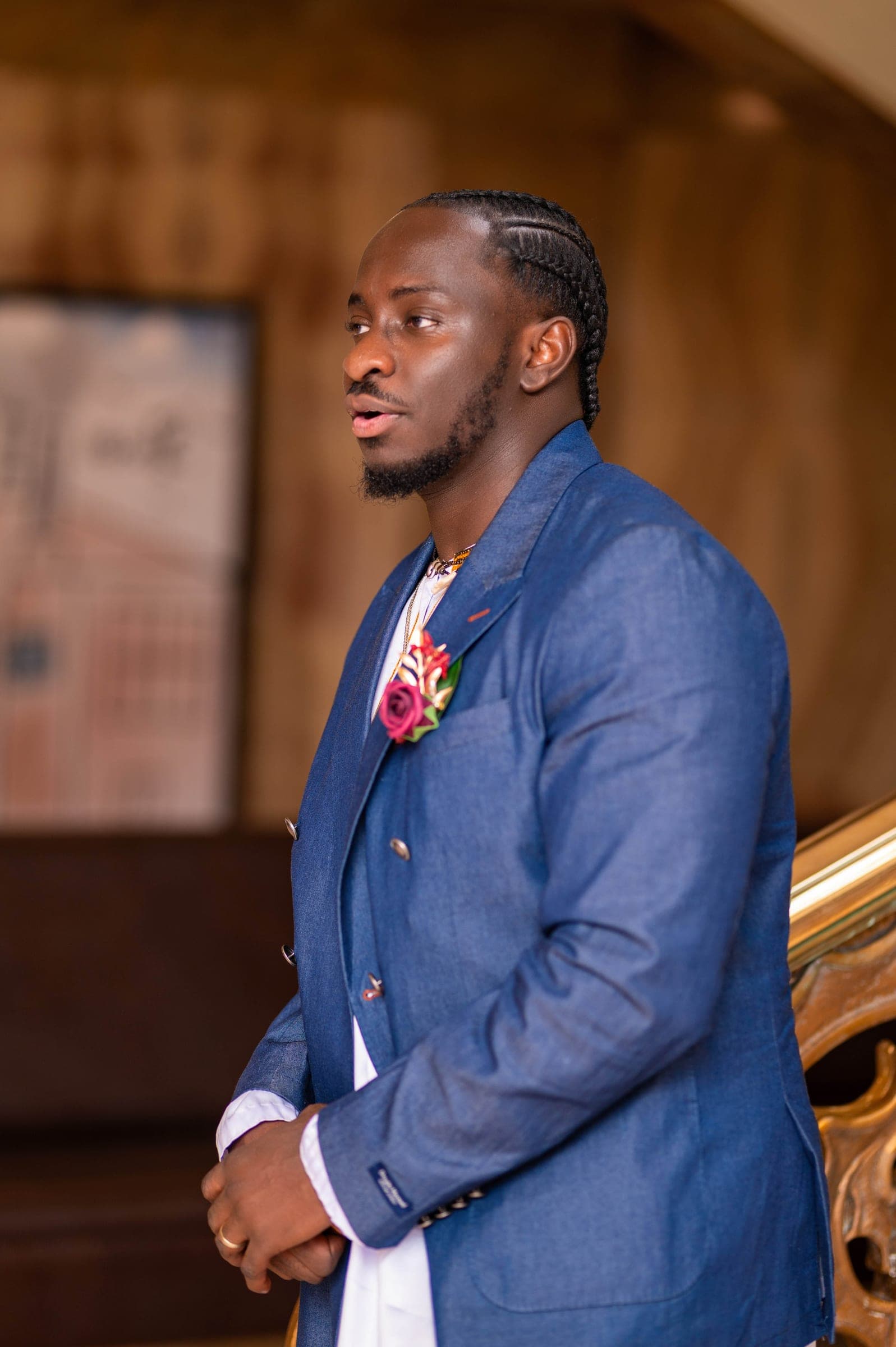A portrait of the groom in his blue denim blazer, looking off to one side in the panelled hall.