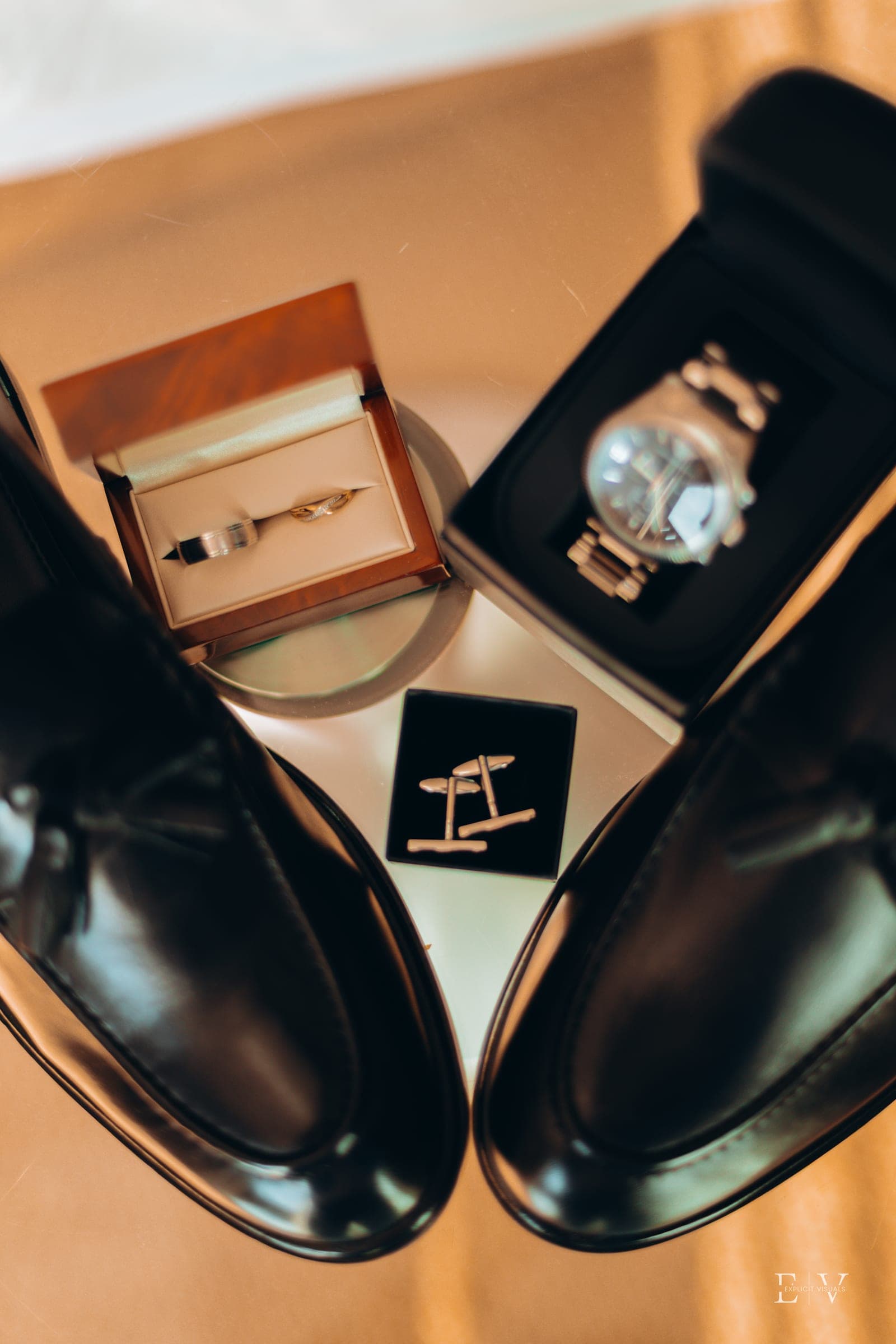 The same flat-lay from above, the two rings in their box between the shoes.