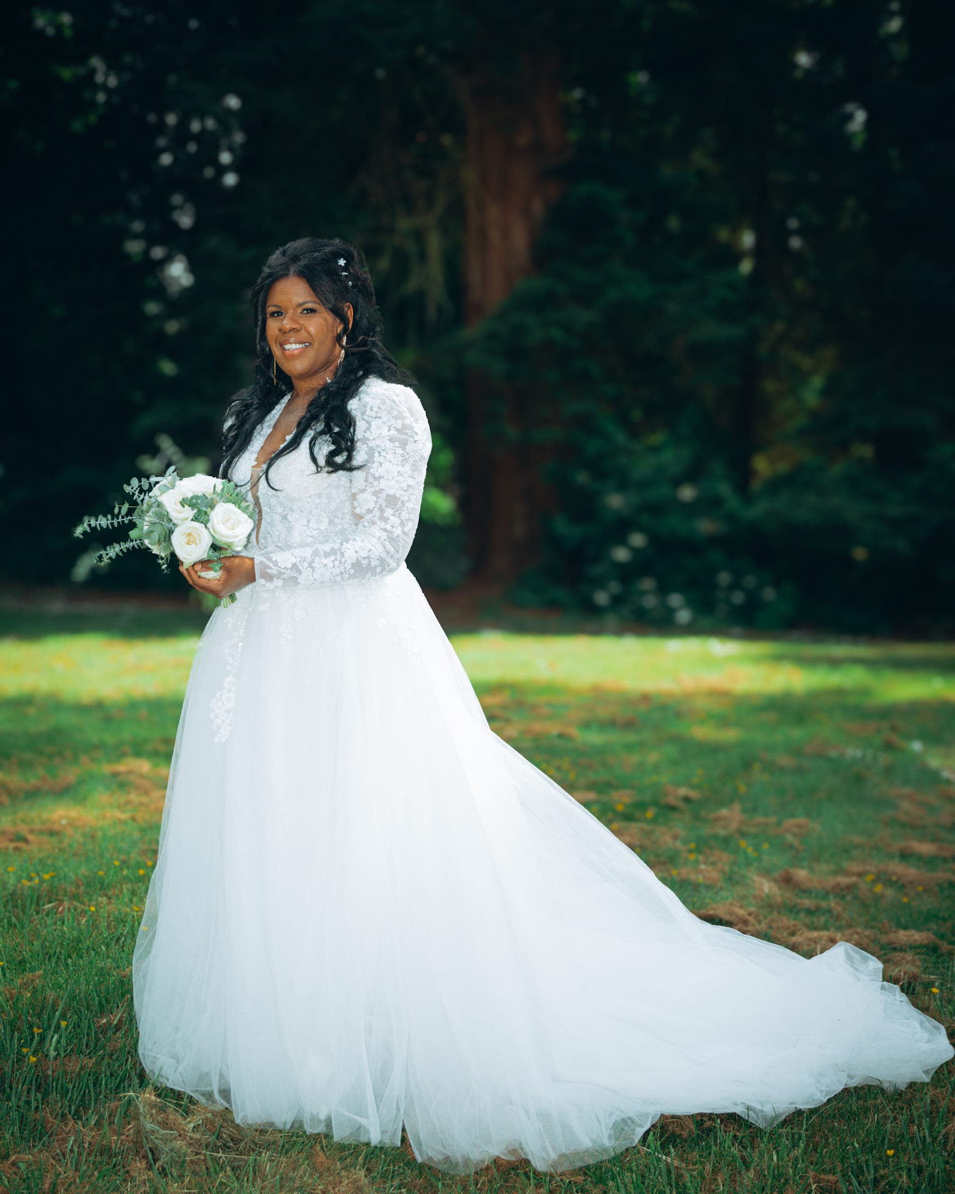 The bride turned side-on, the tulle train of her gown spread out across the grass.